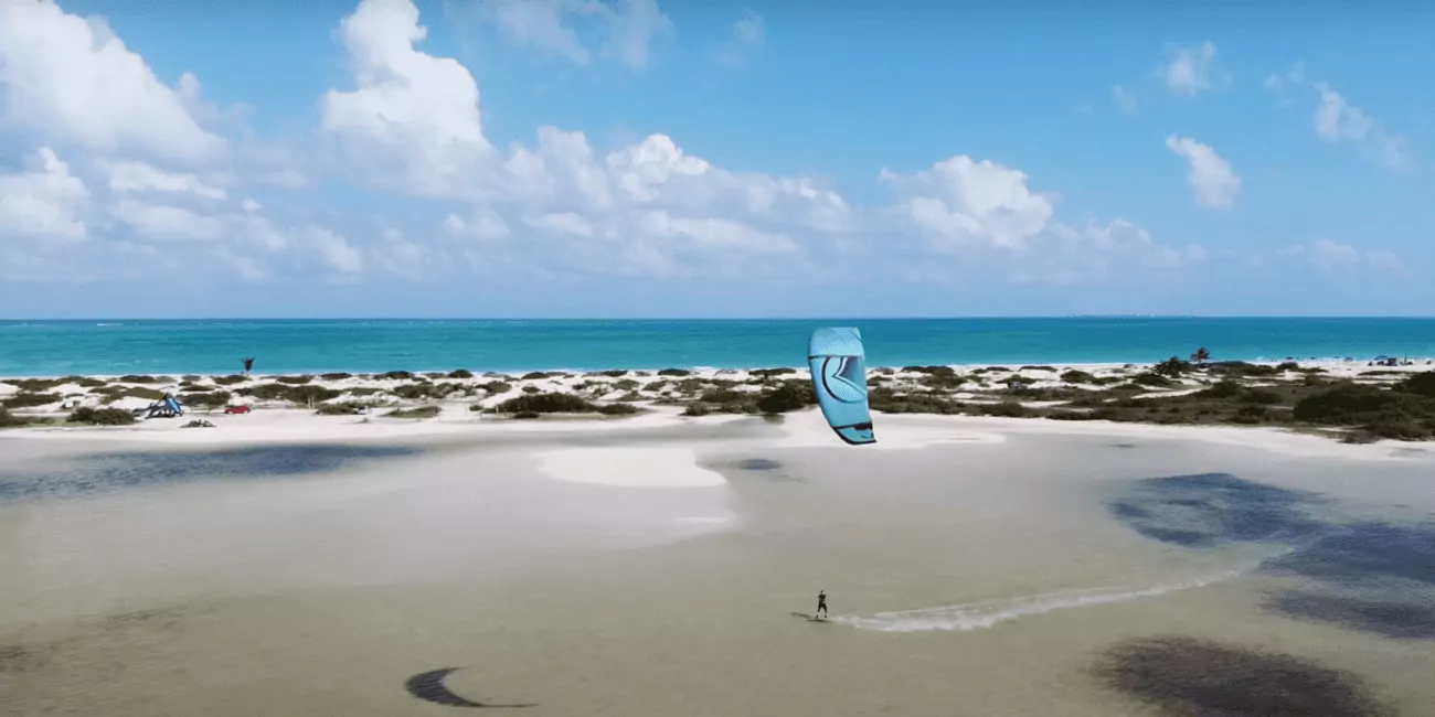 Samotny kitesurfer na płytkiej lagunie, błękitne niebo i krystalicznie czysta woda