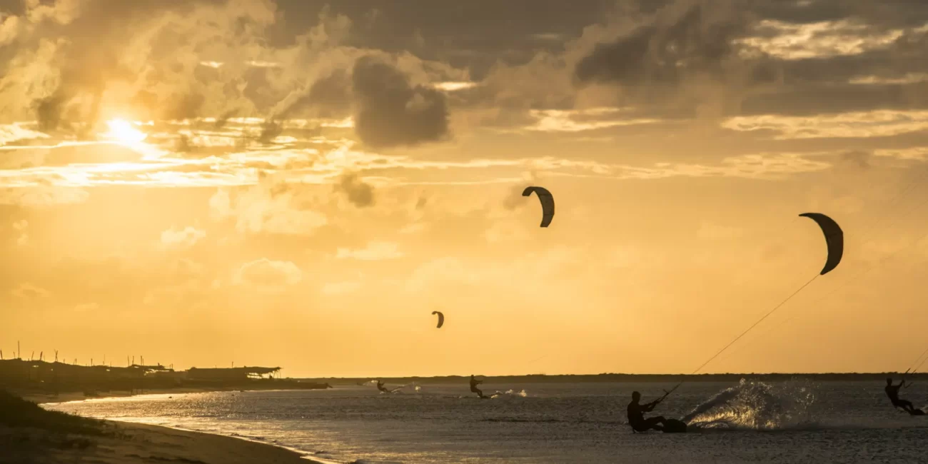 Piękny zachód słońca z trzema kitesurferami pływającymi na płaskiej wodzie podczas Sri Lanka Family Camp